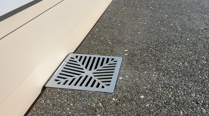 Allproof square plastic drainage pit with aluminium grate installed in concrete